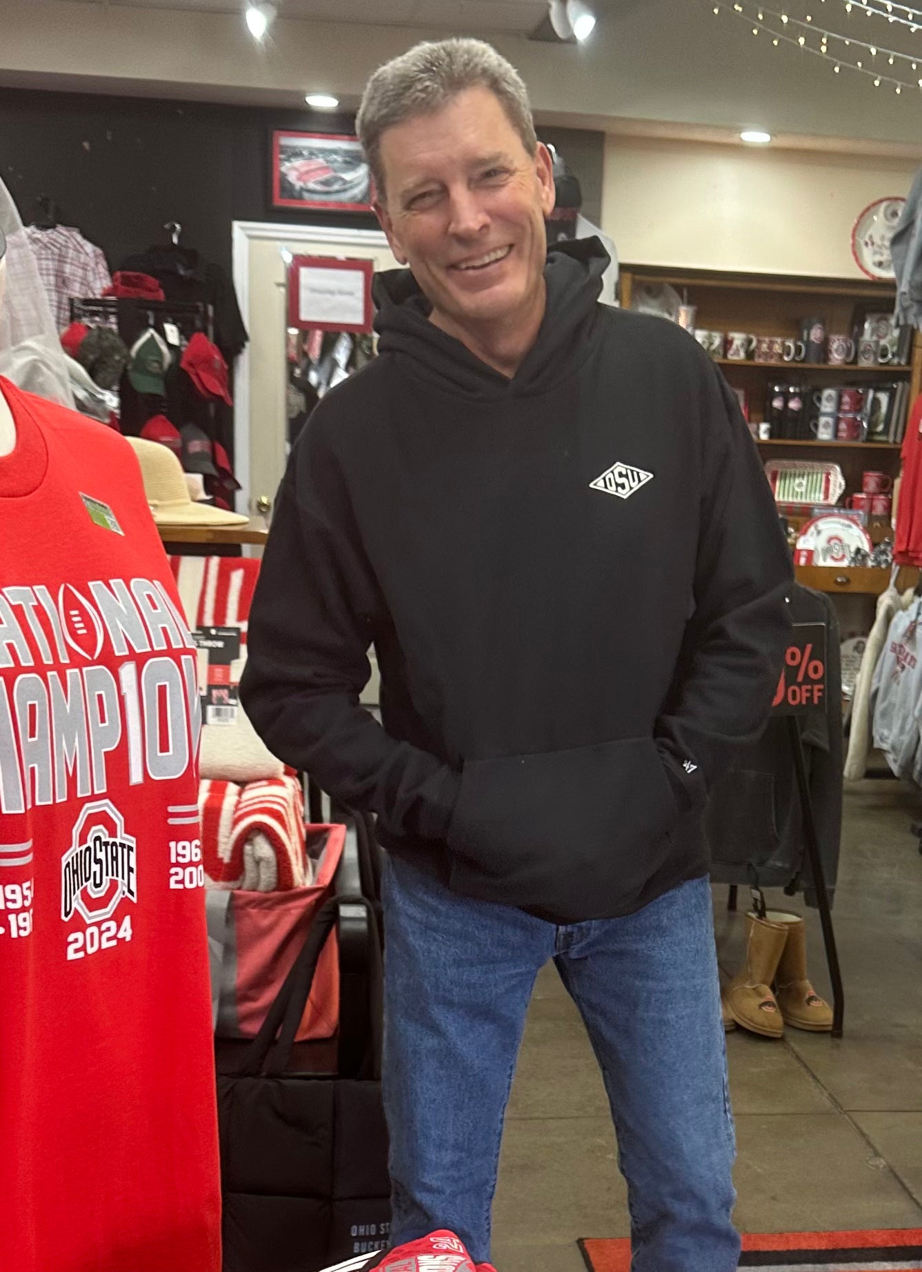 Man wearing a black hoodie with a logo in a store setting