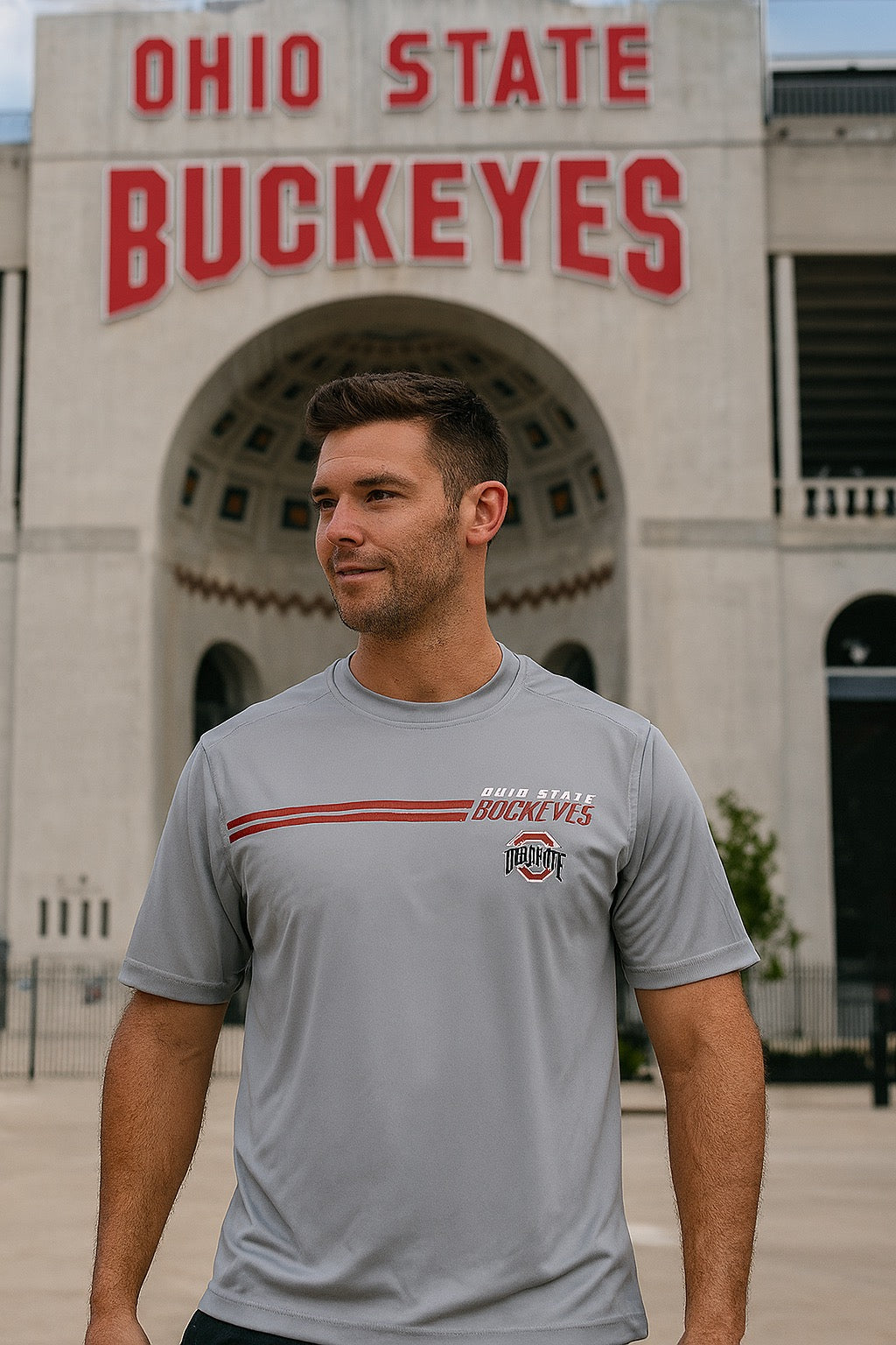 Man wearing a gray t-shirt with Ohio State Buckeyes logo in front of a building with the same logo.