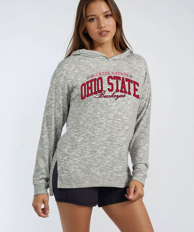 A woman modeling a heather gray hooded sweatshirt with 'OHIO STATE Buckeyes' printed in red and black across the chest, paired with black athletic shorts, against a light gray studio background.
