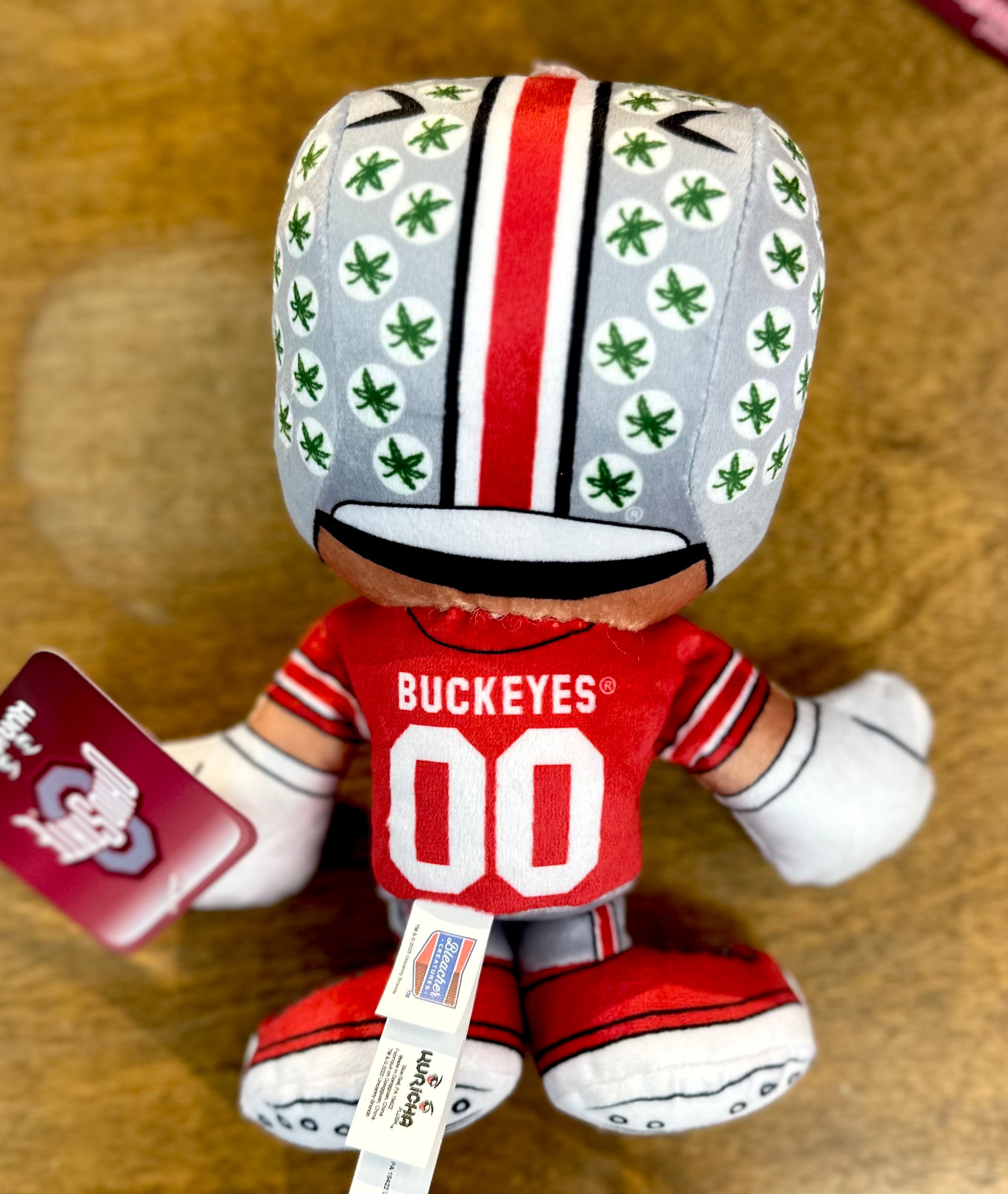 Plush toy with Ohio State Buckeyes uniform on a brown surface