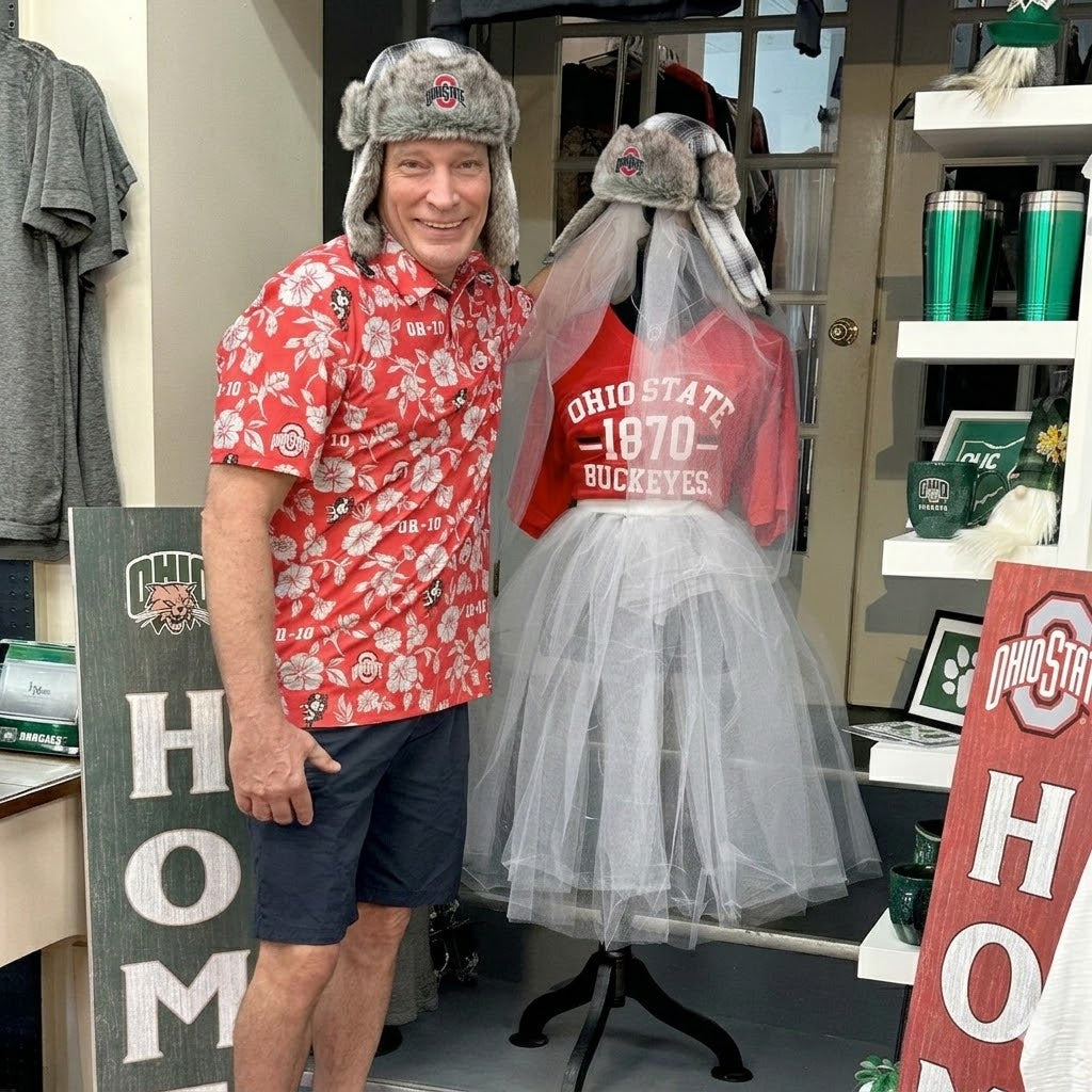Man wearing a red floral shirt and gray fur hat standing next to a mannequin with an Ohio State shirt in a store.