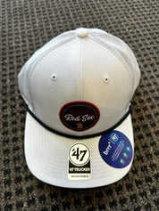 White baseball cap with 'Red Sox' and '47' branding on a textured surface