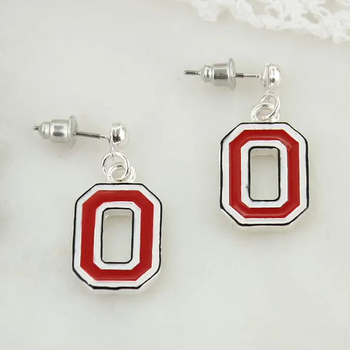 A pair of silver stud earrings featuring a large letter 'O' design in red, white, and black enamel, displayed on a clean white surface.