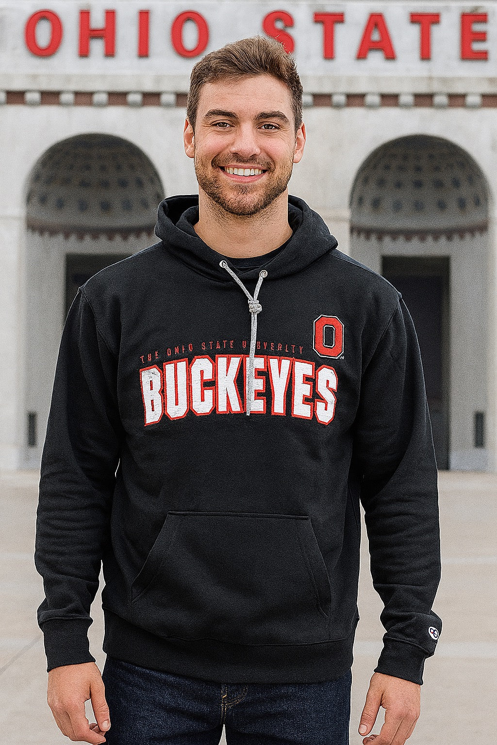 Person wearing a black Ohio State Buckeyes hoodie in front of a building with 'Ohio State' on top.