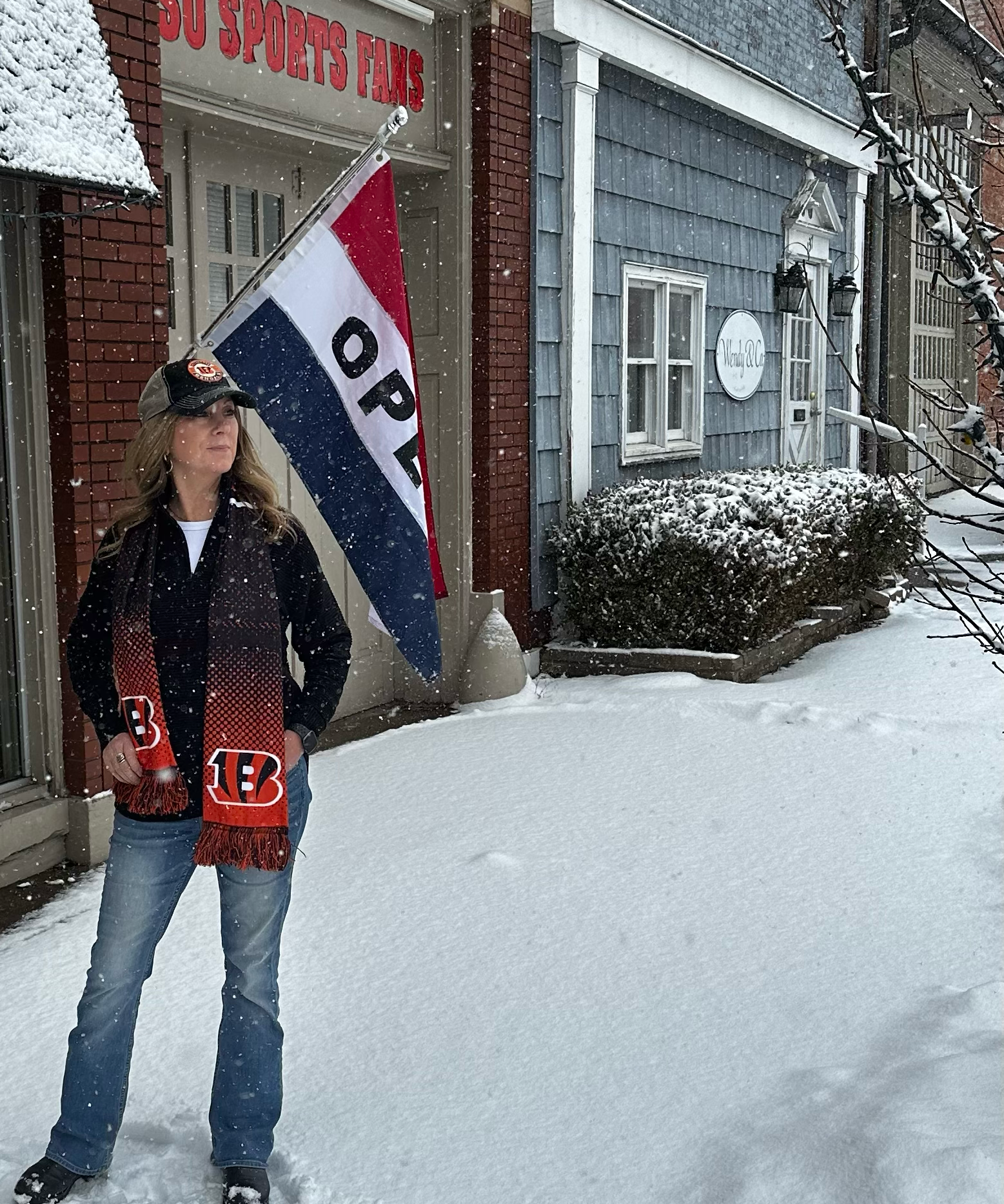 Person holding a flag with 'Open' text in front of a building with snow on the ground