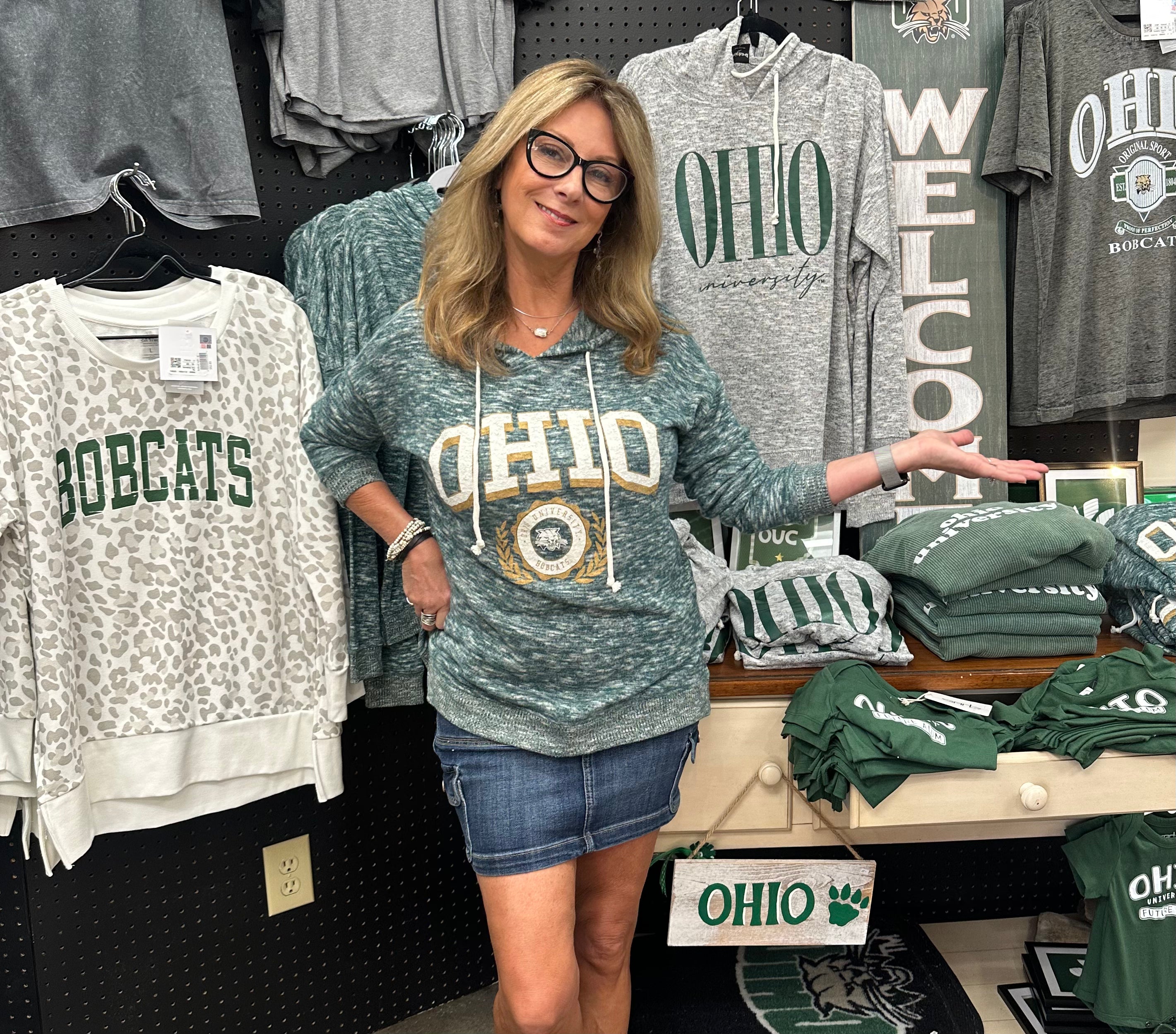 Woman wearing a 'OHIO' sweatshirt in a store with various merchandise.