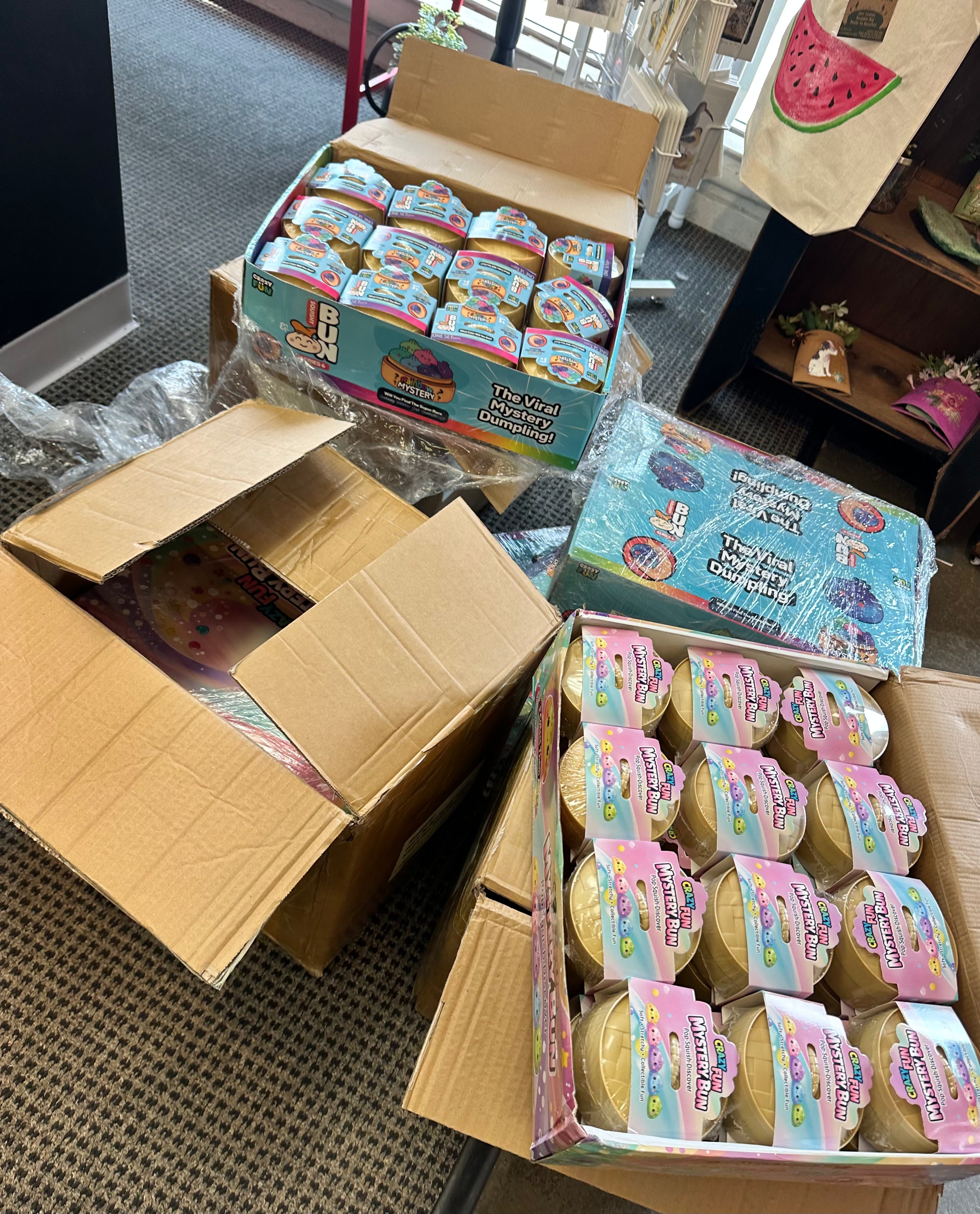 Open cardboard boxes filled with small containers on a floor.