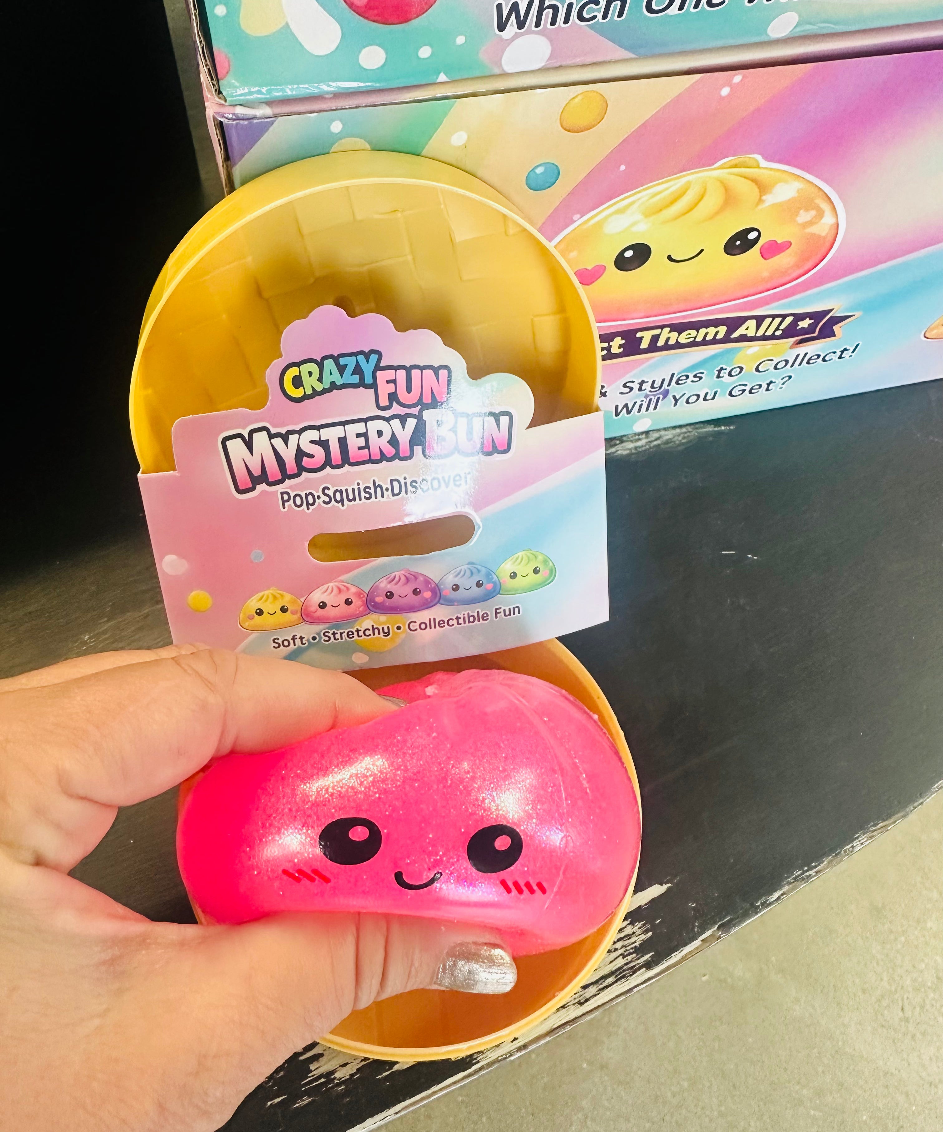 Pink squishy toy with a 'Crazy Fun Mystery Bin' packaging in front of a colorful box.