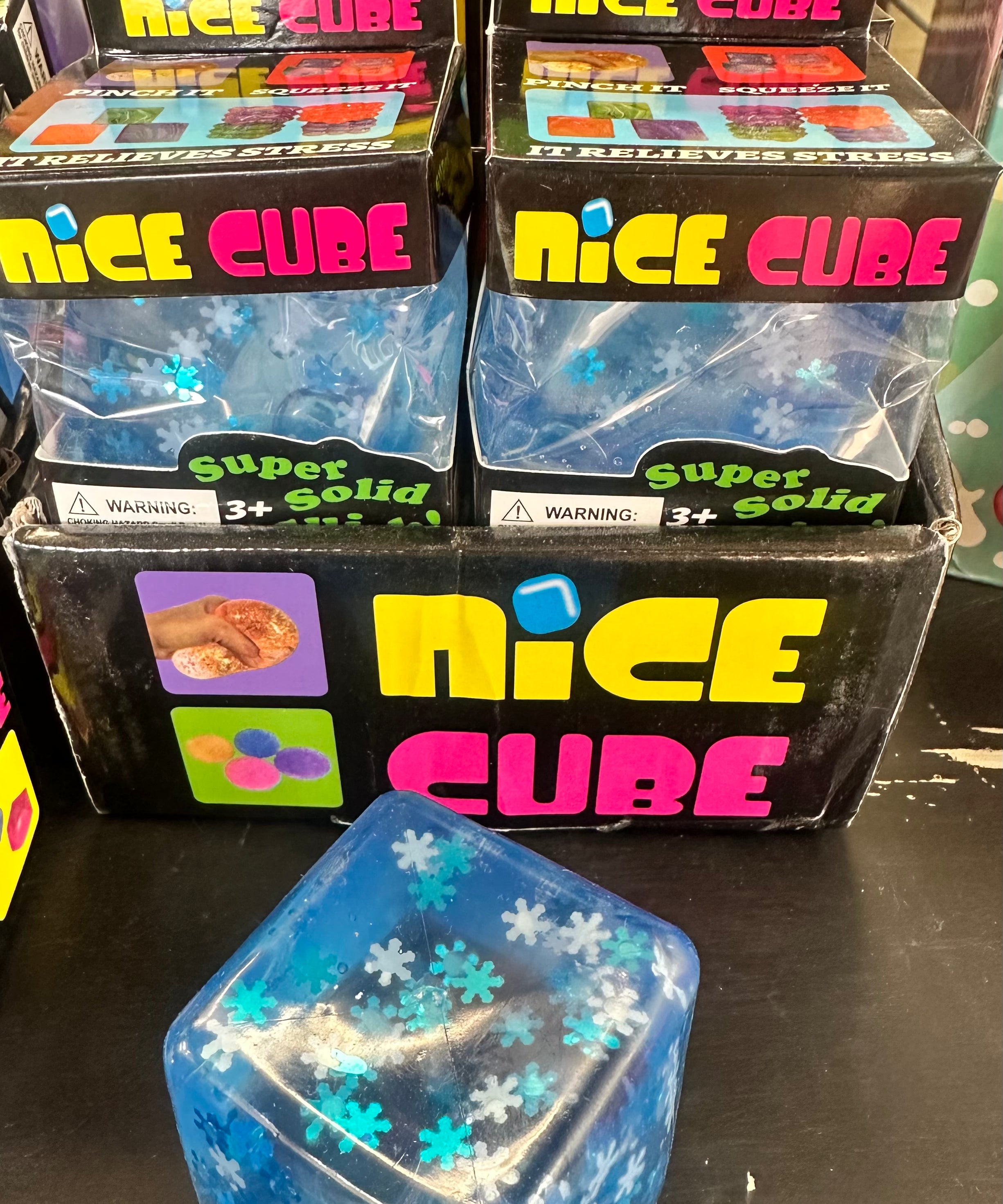 Blue 'Nice Cube' product with packaging on a black surface
