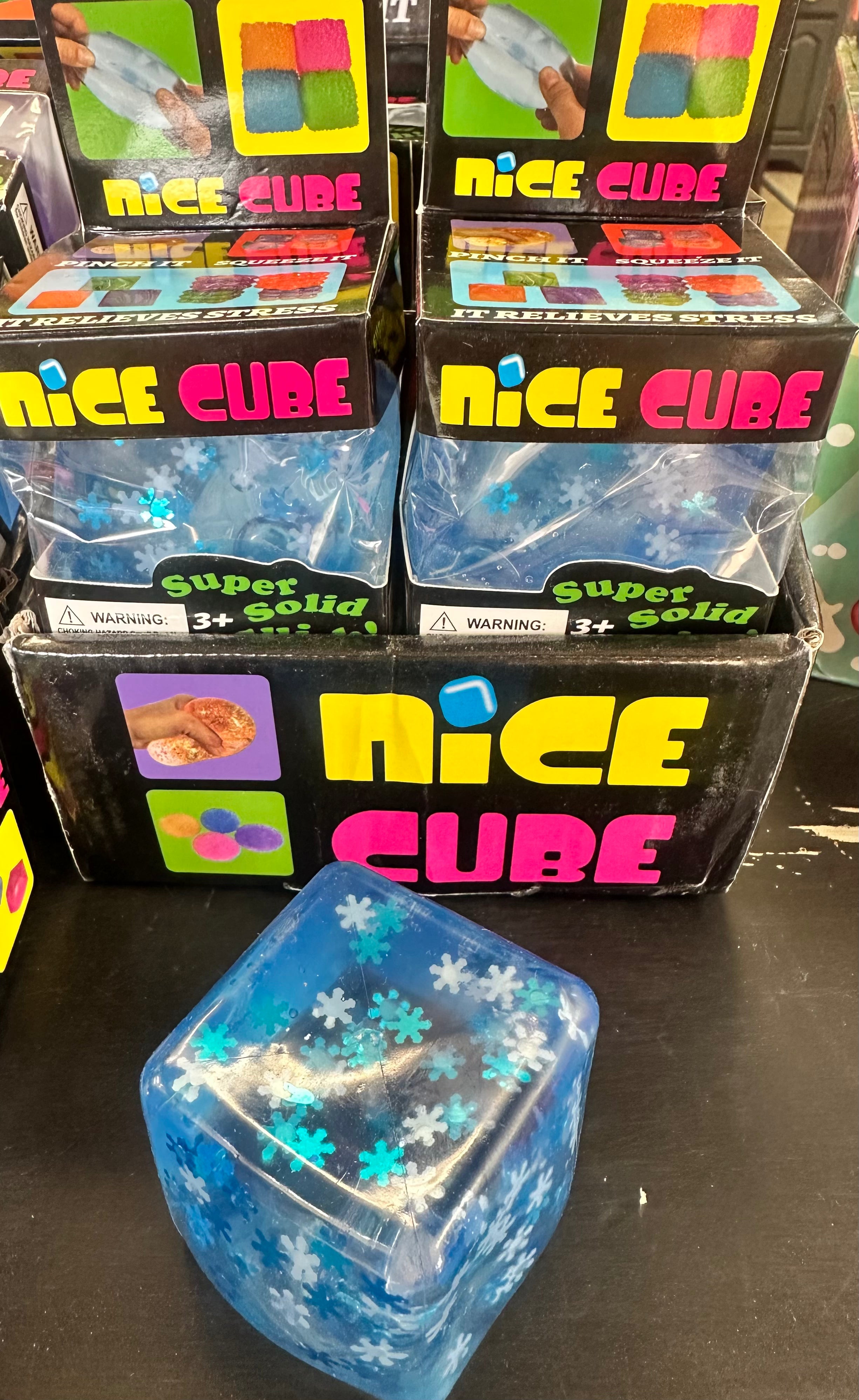 Blue 'Nice Cube' product with packaging on a black surface