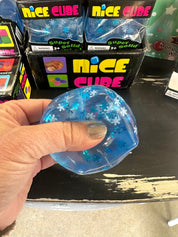 Blue glittery cube held by a hand with packaging labeled 'Nice Cube' in the background.