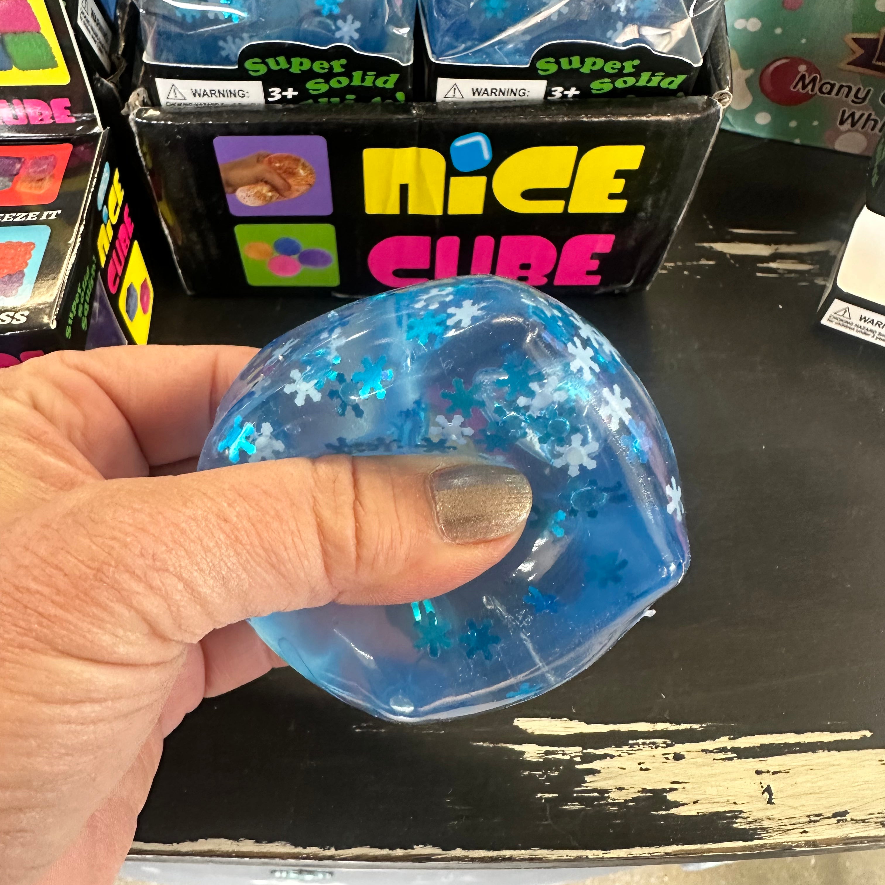 Blue glittery cube held by a hand with packaging labeled 'Nice Cube' in the background.