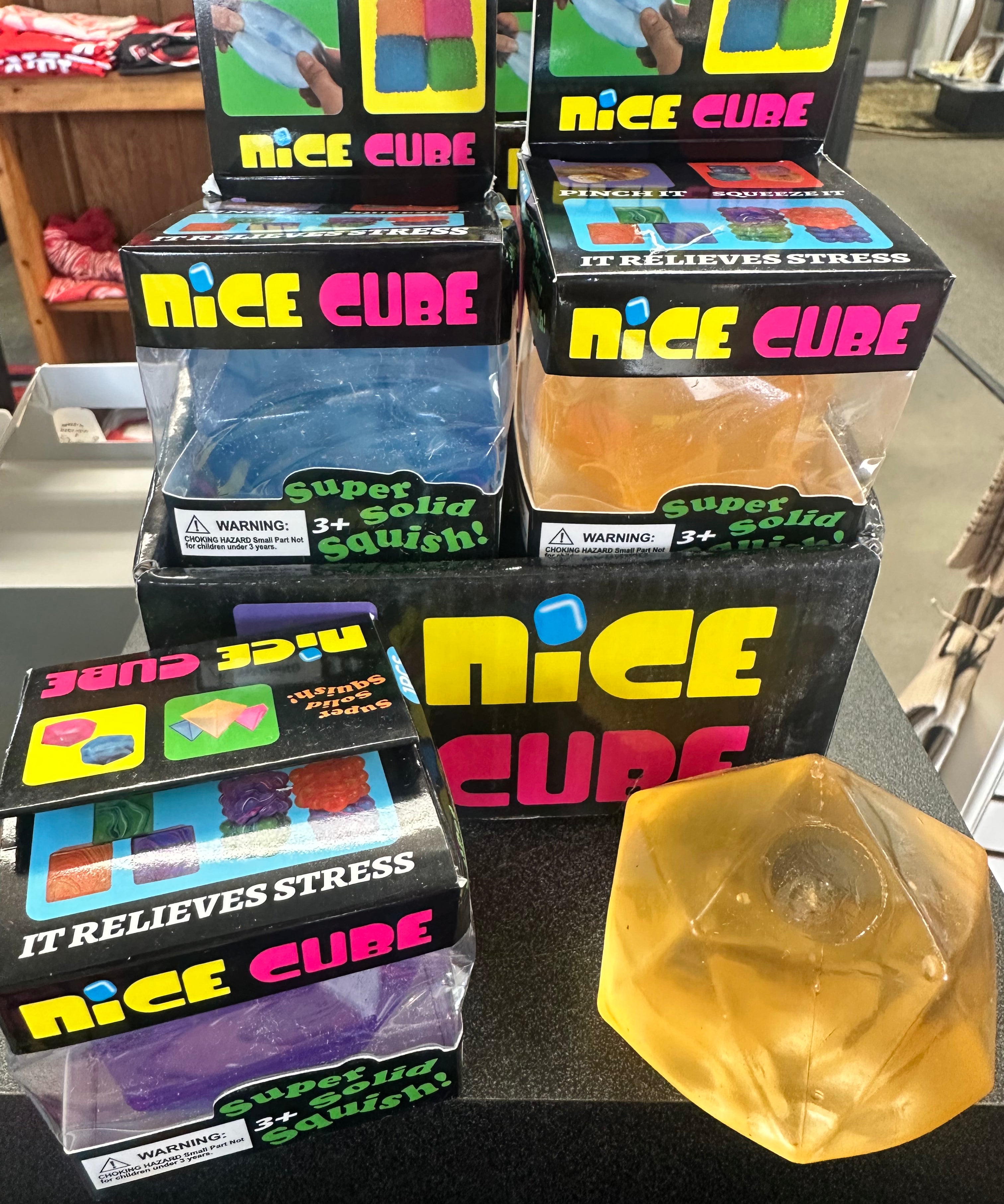 Multiple boxes of 'Nice Cube' stress relievers on a table with one cube removed.