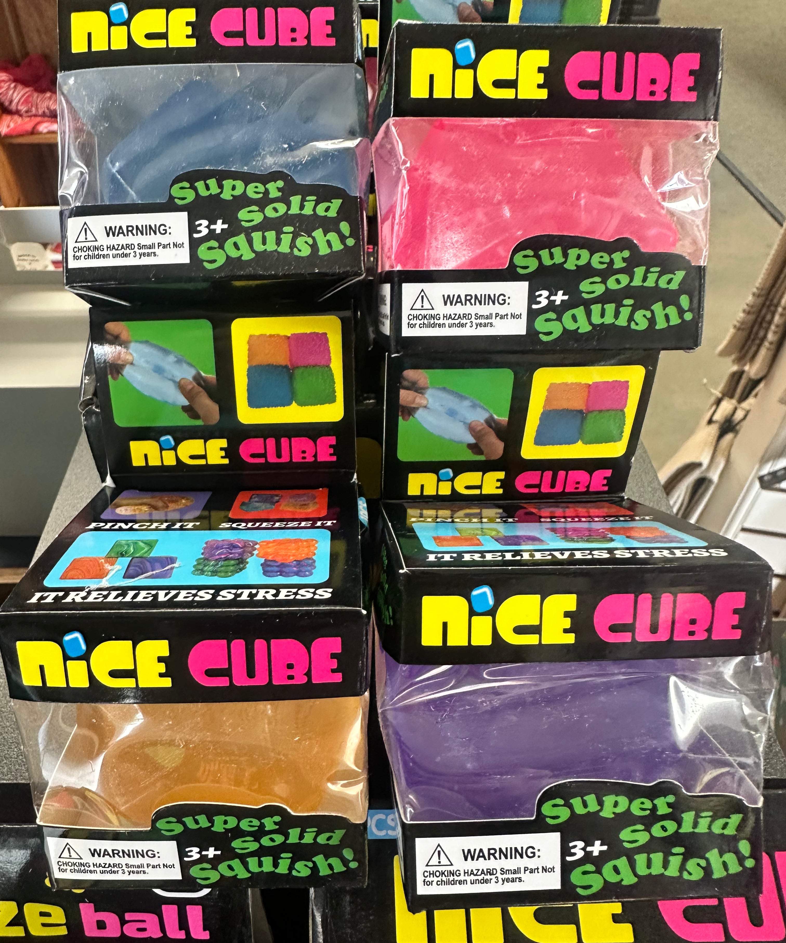 Multiple packages of 'Nice Cube' stress balls on a shelf with colorful packaging.