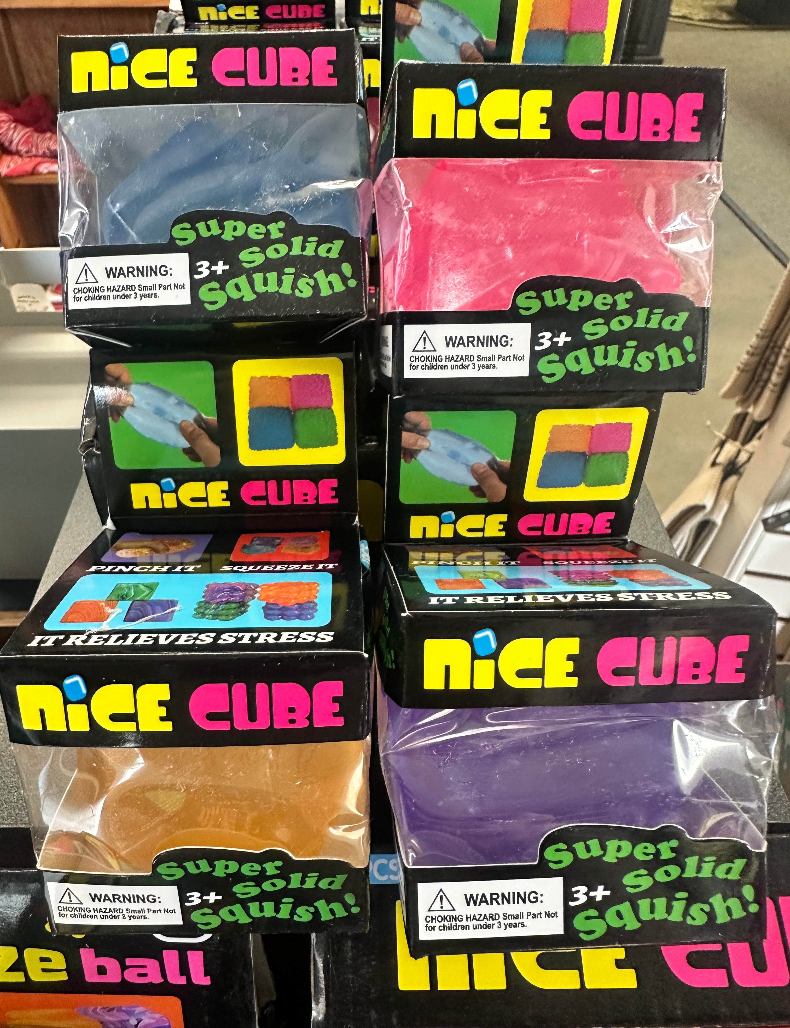 Multiple packages of 'Nice Cube' stress balls on a shelf with colorful packaging.