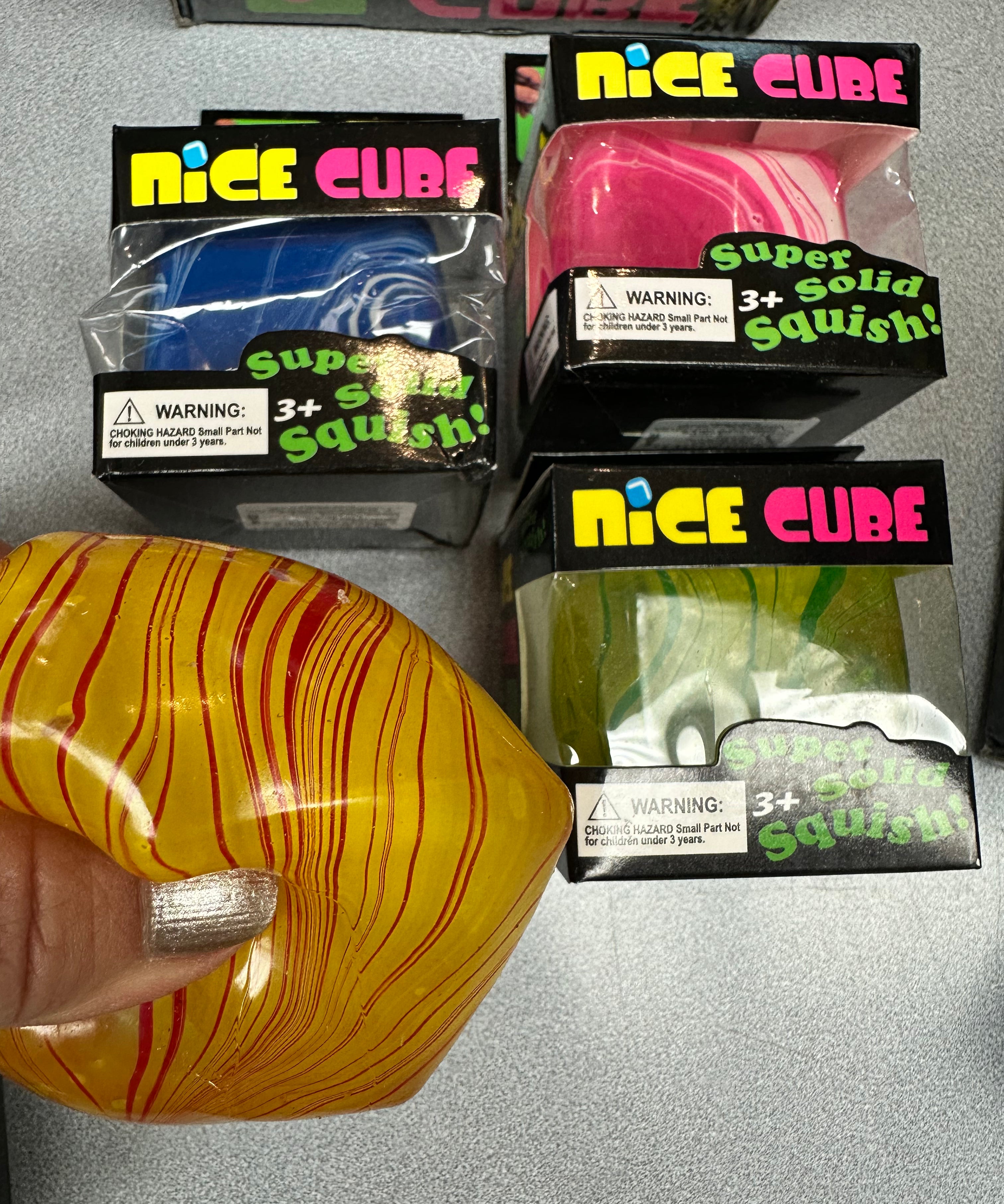 Colorful squishy cubes with packaging labeled 'Nice Cube' on a gray surface.