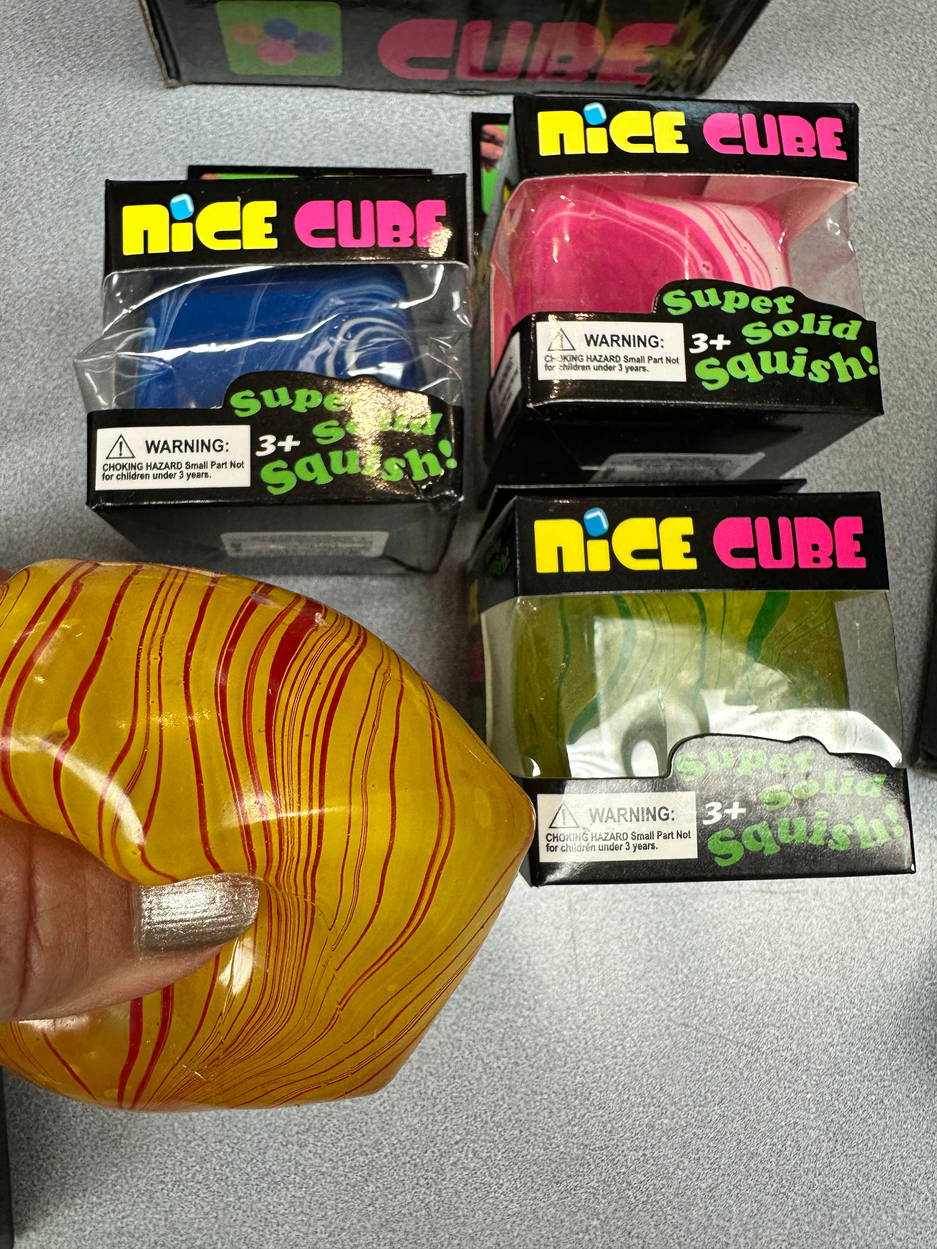 Colorful squishy cubes with packaging labeled 'Nice Cube' on a gray surface.