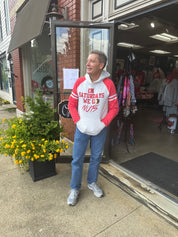 Man wearing a red and white hoodie standing outside a store with sweatshirt On Saturdays We Go Nuts.