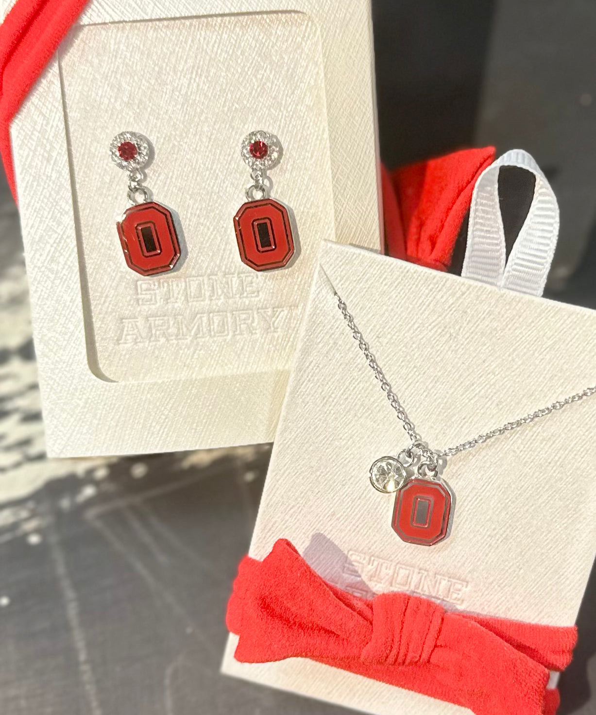 Jewelry set with earrings and necklace on display cards, featuring a red and silver design.