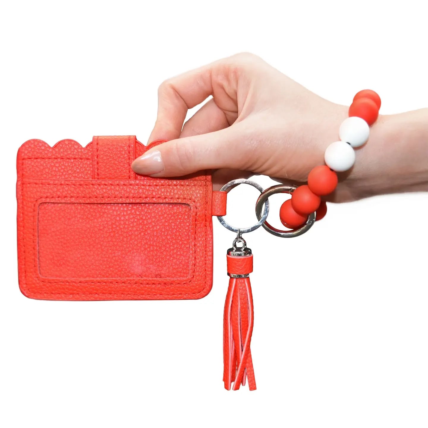Red cardholder with tassel and keychain held by a hand on a white background